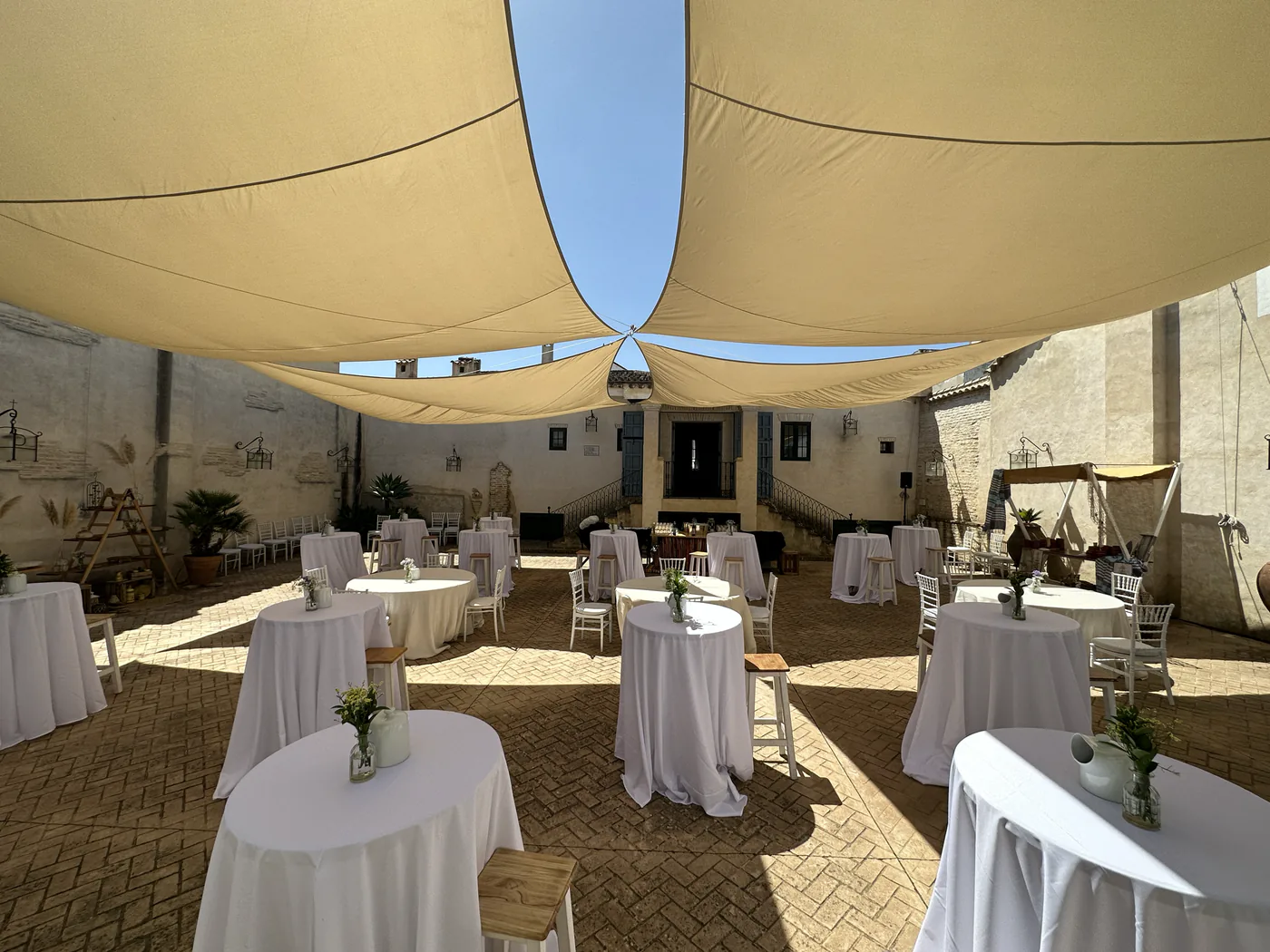 Patio preparado para un cóctel bajo los toldos de la hacienda