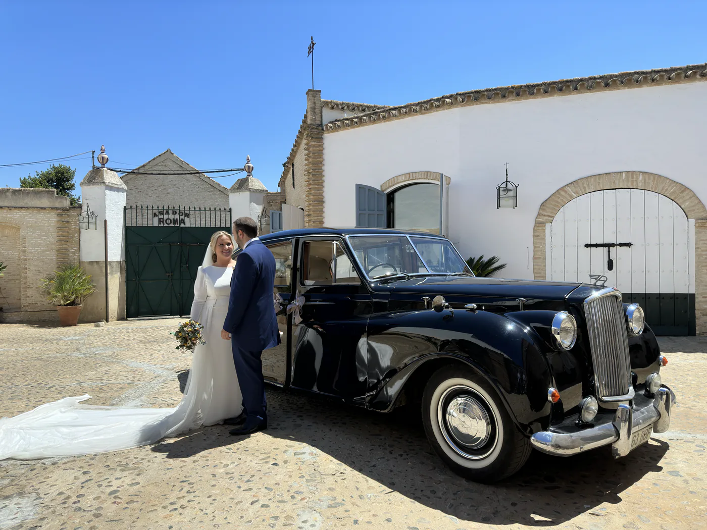 Pareja de recién casados junto a un coche clásico en la hacienda